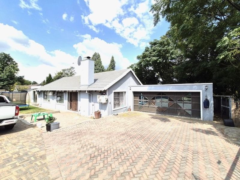 Exterior view of the property featuring a paved driveway, attached garage with decorative doors, and a tiled roof structure.