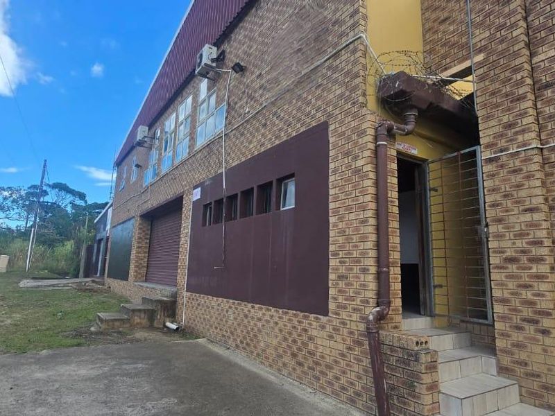 Commercial building exterior featuring face brick facade, roller shutter access, and security installations.