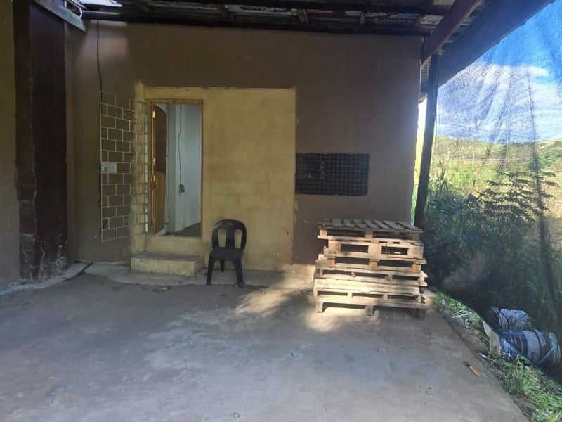 An outdoor covered patio area featuring concrete flooring and shade cloth screening, providing a basic utility space with potential for improvement.