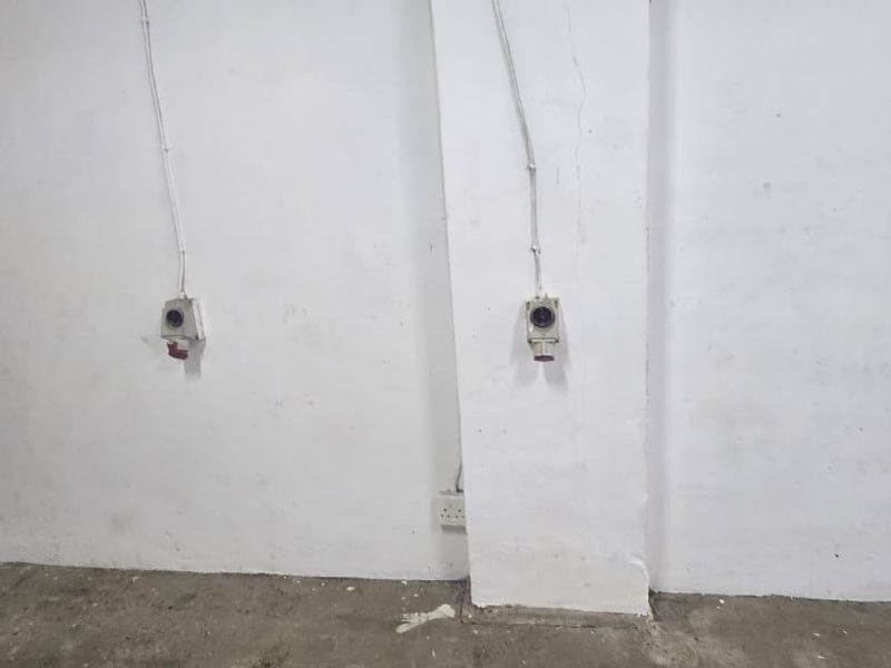 A utilitarian space featuring concrete flooring and industrial electrical power points, suitable for storage or workshop use.