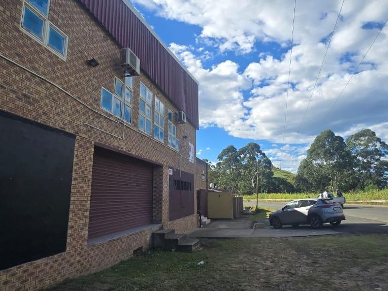Exterior view of a commercial property featuring a face brick facade, roller shutter door, and metal cladding with integrated air conditioning units.