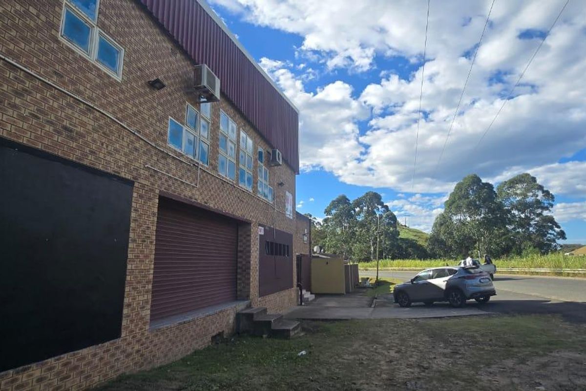 Exterior view of a commercial property featuring a face brick facade, roller shutter door, and metal cladding with integrated air conditioning units.