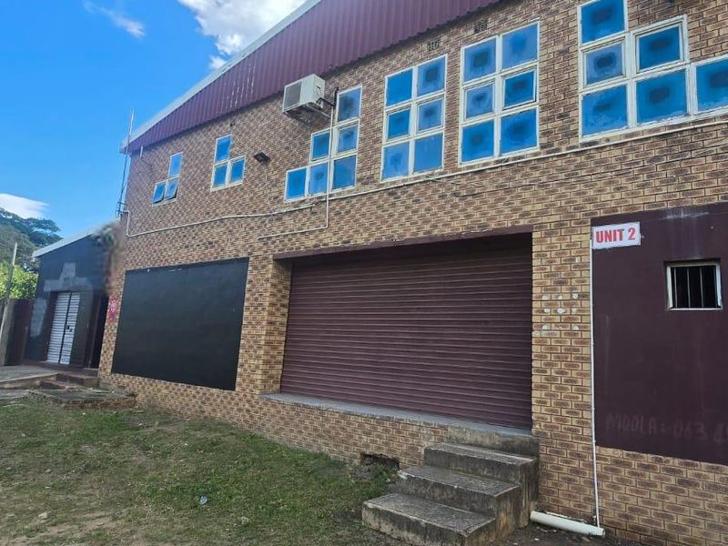 Commercial property exterior featuring a face brick facade, roller shutter door access, and an installed air conditioning unit.