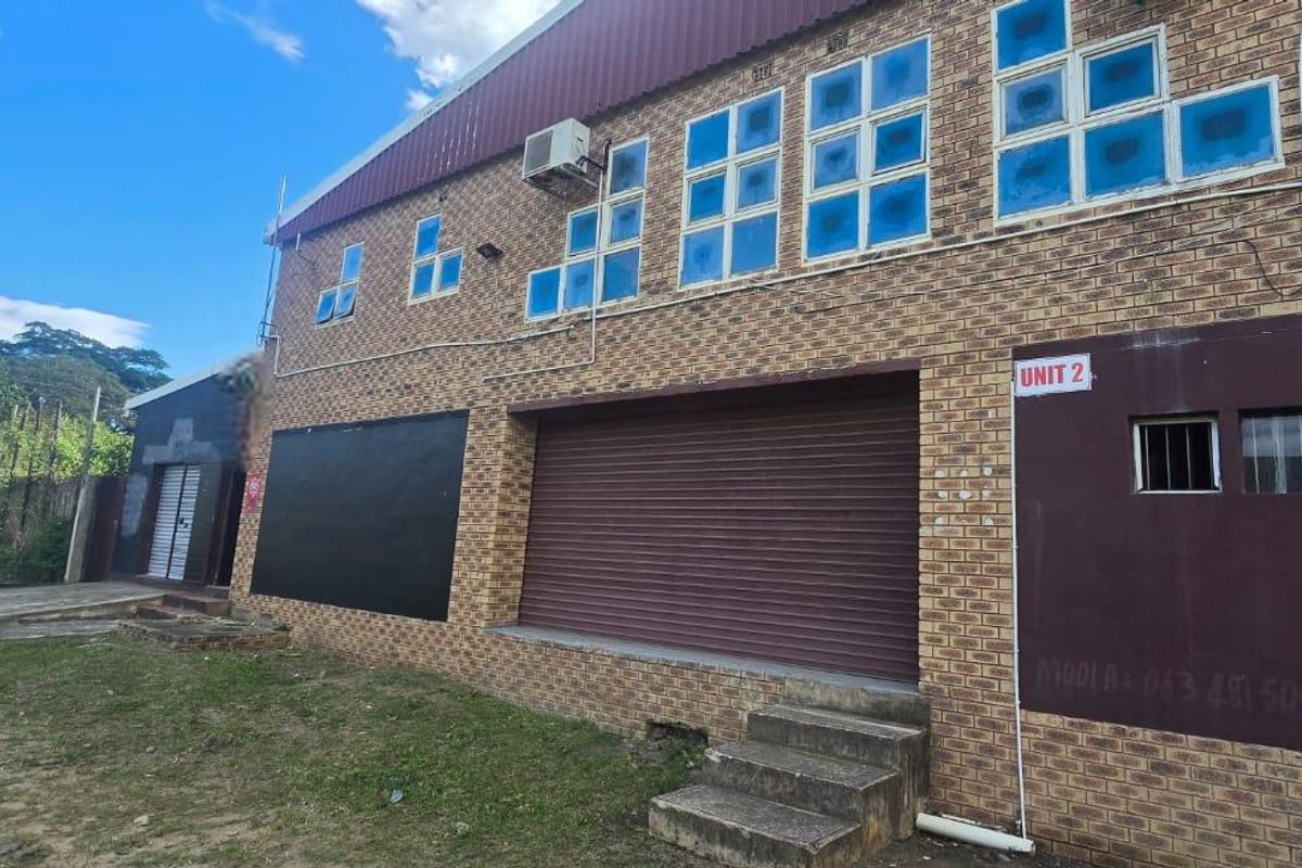 Commercial property exterior featuring a face brick facade, roller shutter door access, and an installed air conditioning unit.