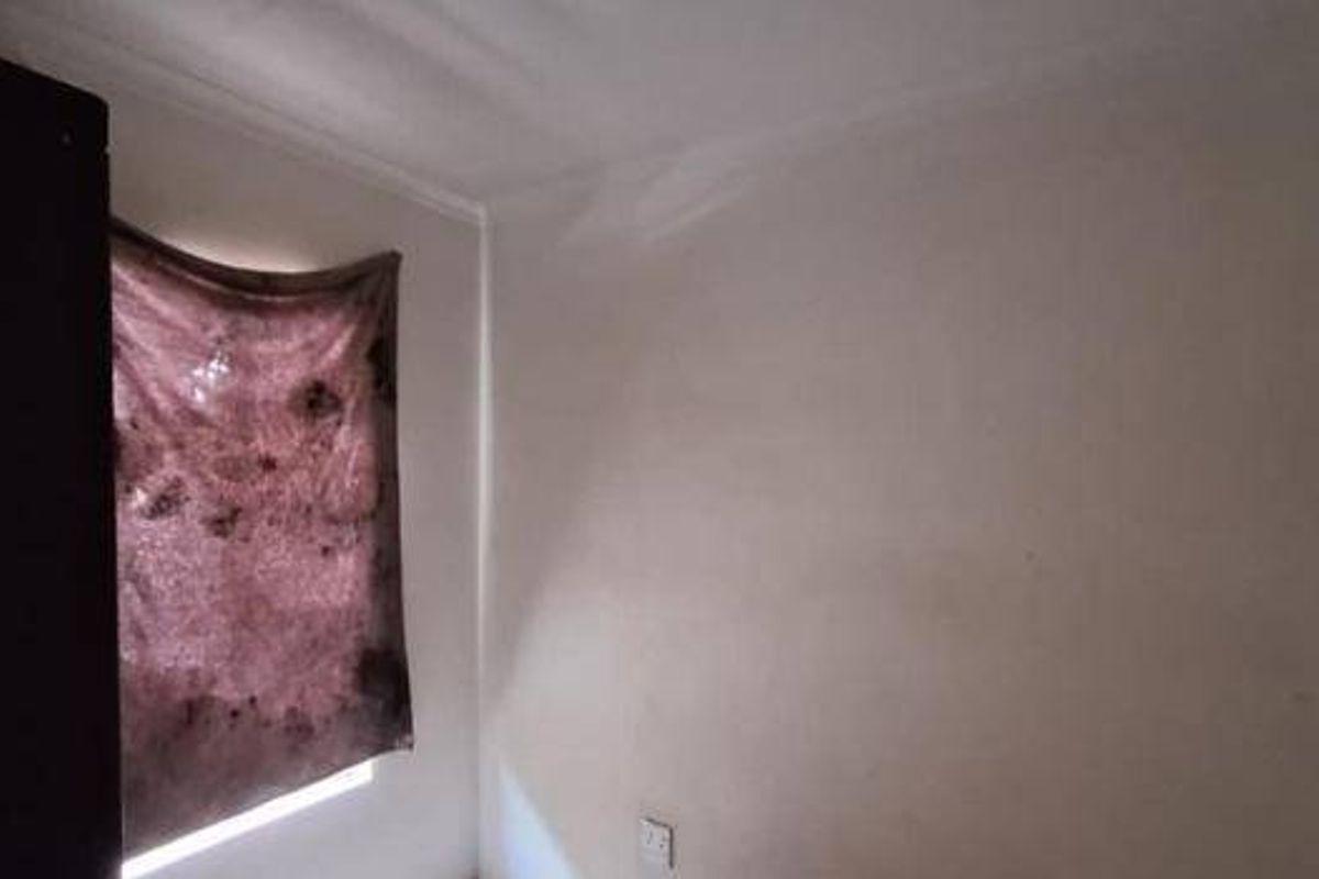 A small, empty bedroom featuring a built-in cupboard and plain wall finishes, requiring cosmetic updates to improve its overall appeal.