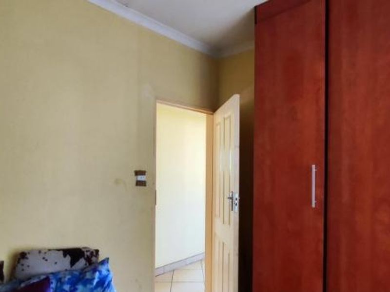 A bedroom featuring built-in wooden cupboards and yellow painted walls, requiring minor cosmetic updates to improve the overall aesthetic.