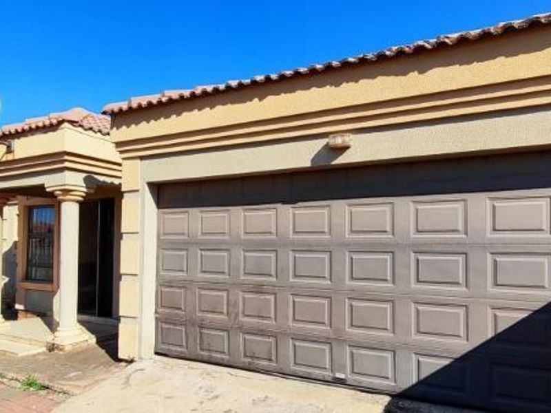 Front elevation of the house featuring a single garage, paved driveway, and a covered entrance porch with decorative columns.