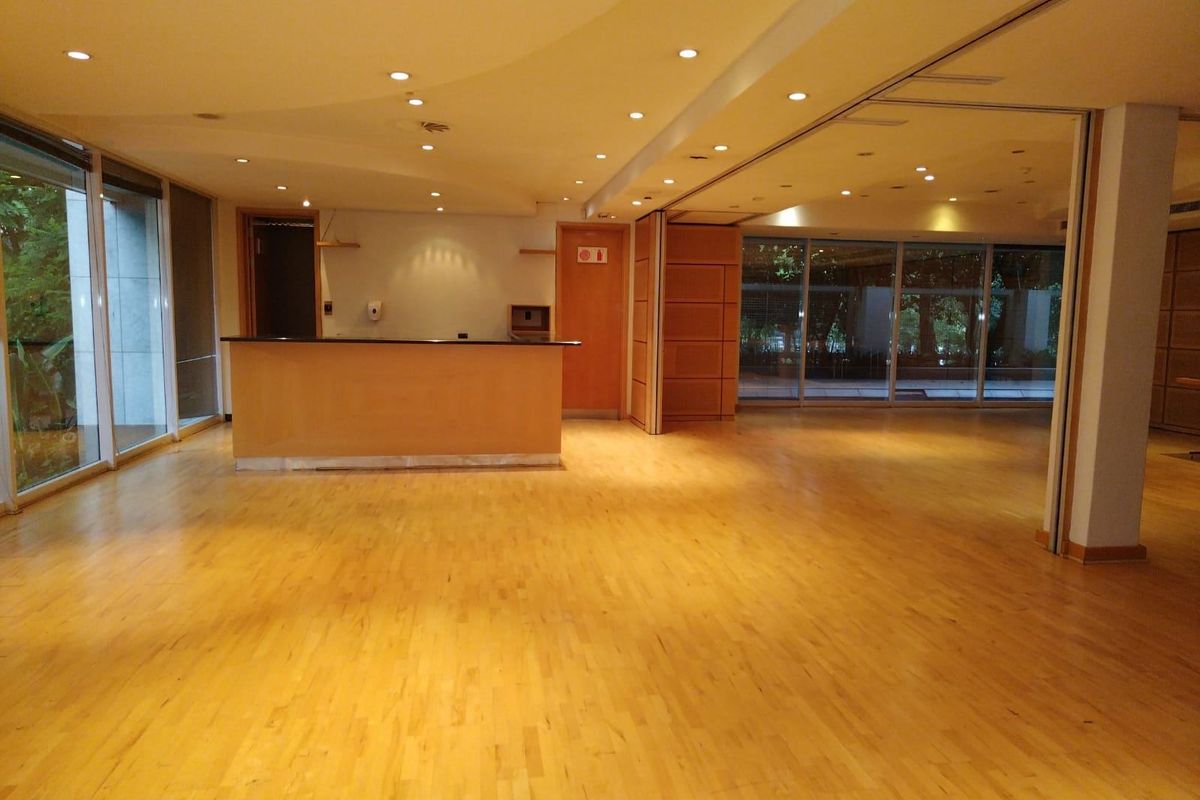 Spacious open-plan commercial area featuring polished hardwood flooring, recessed lighting, a built-in service counter, and large sliding glass doors providing natural light.