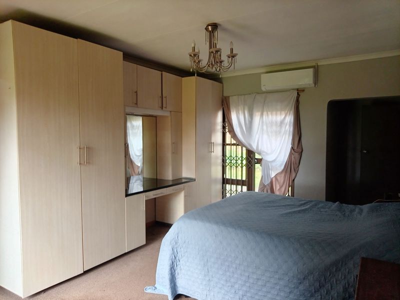 Spacious bedroom featuring extensive built-in cabinetry with an integrated vanity, split-system air conditioning, and direct access to an outdoor area via a security gate.