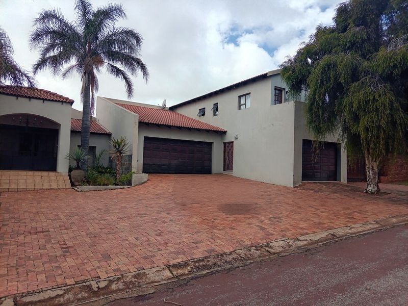 Front elevation of a multi-level house featuring a paved driveway, double and single garages, and a tiled roof.
