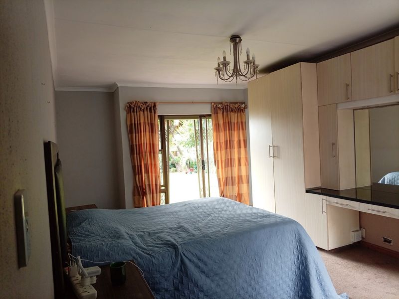 A bedroom featuring built-in cupboards, a vanity area, and a sliding glass door providing access to the garden.
