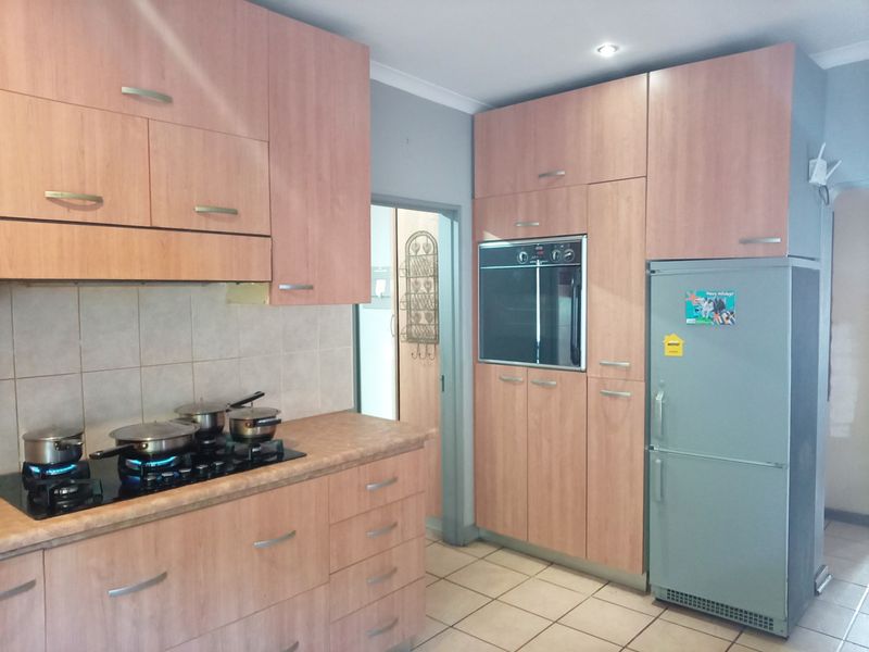 A functional kitchen featuring wood-look cabinetry, laminate countertops, a built-in oven, and a gas hob with a tiled backsplash.