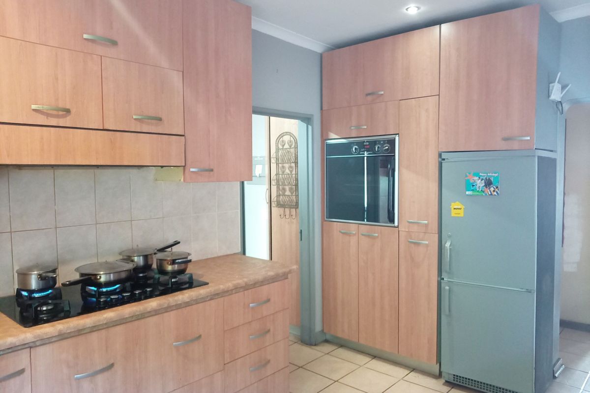 A functional kitchen featuring wood-look cabinetry, laminate countertops, a built-in oven, and a gas hob with a tiled backsplash.