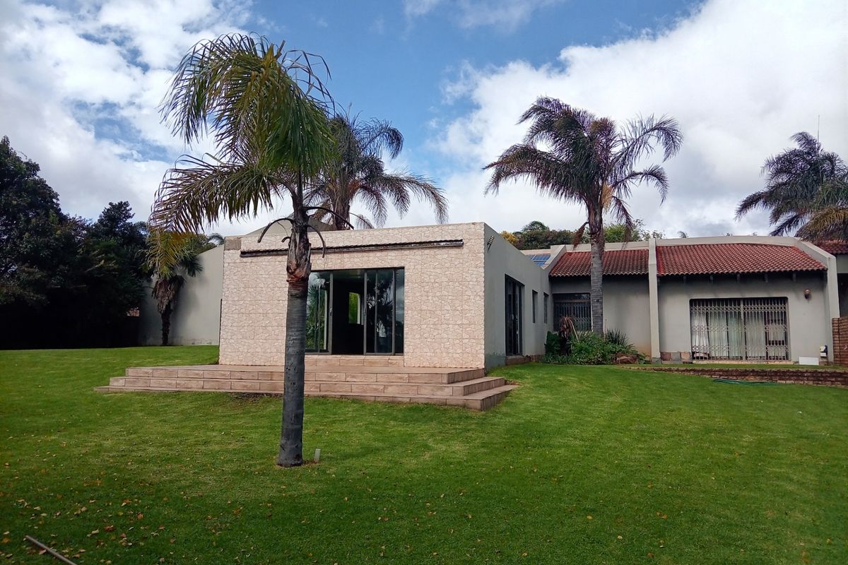 Rear view of the property featuring a stone-clad extension, sliding glass doors, tiled patio steps, and a spacious lawn area.