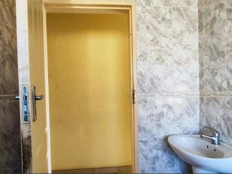 A small bathroom featuring a pedestal basin with chrome mixer tap and full-height marble-effect ceramic wall tiling.