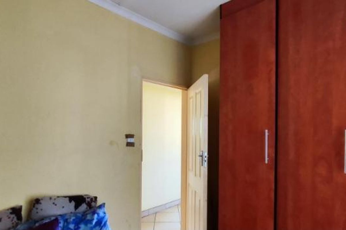 A bedroom featuring built-in wooden cupboards and yellow painted walls, requiring minor cosmetic updates to improve the overall aesthetic.