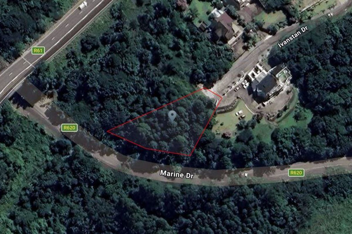 An aerial view of a vacant residential plot surrounded by dense vegetation, located near Marine Drive and Ivanstan Drive.