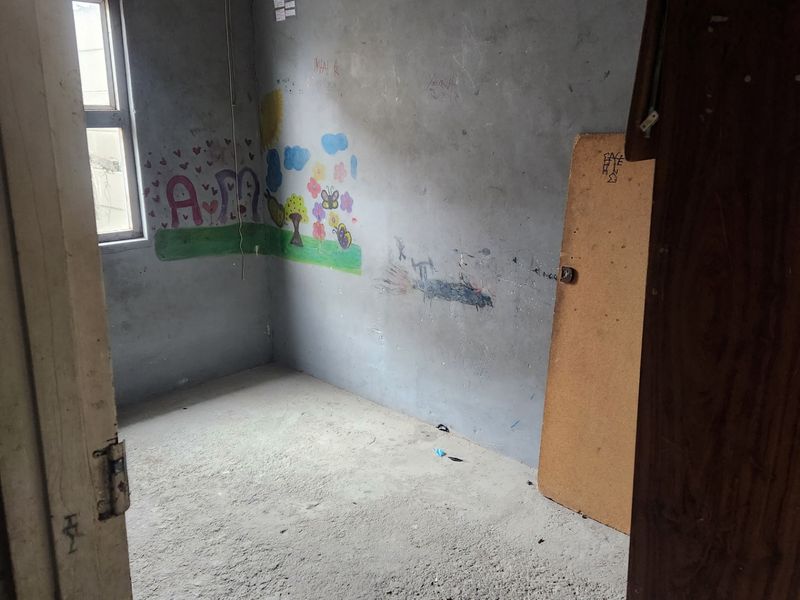 A vacant bedroom featuring unfinished concrete flooring and walls requiring cosmetic repair and repainting.