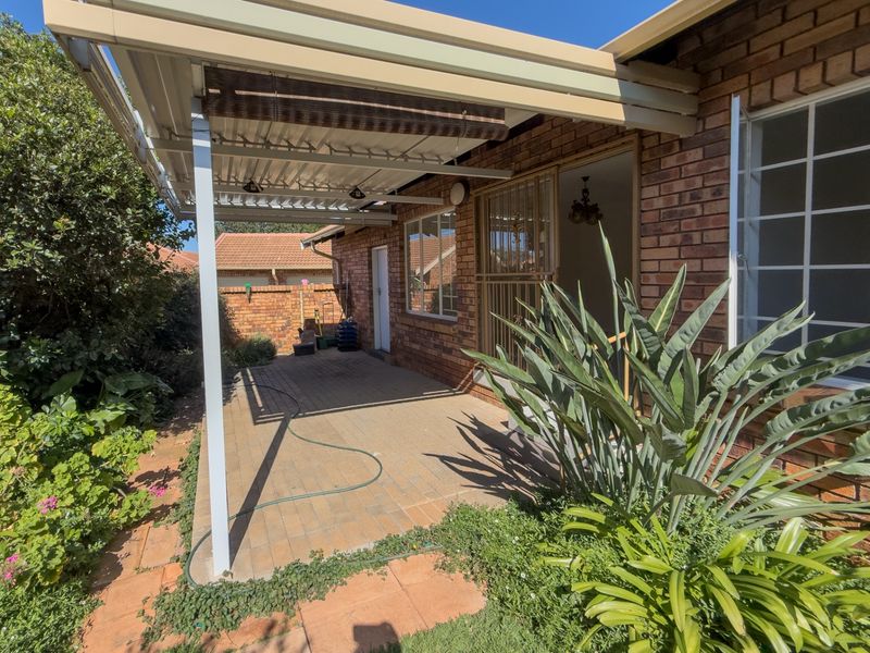 A covered brick patio area with paved flooring, providing a functional outdoor space adjacent to the main dwelling.