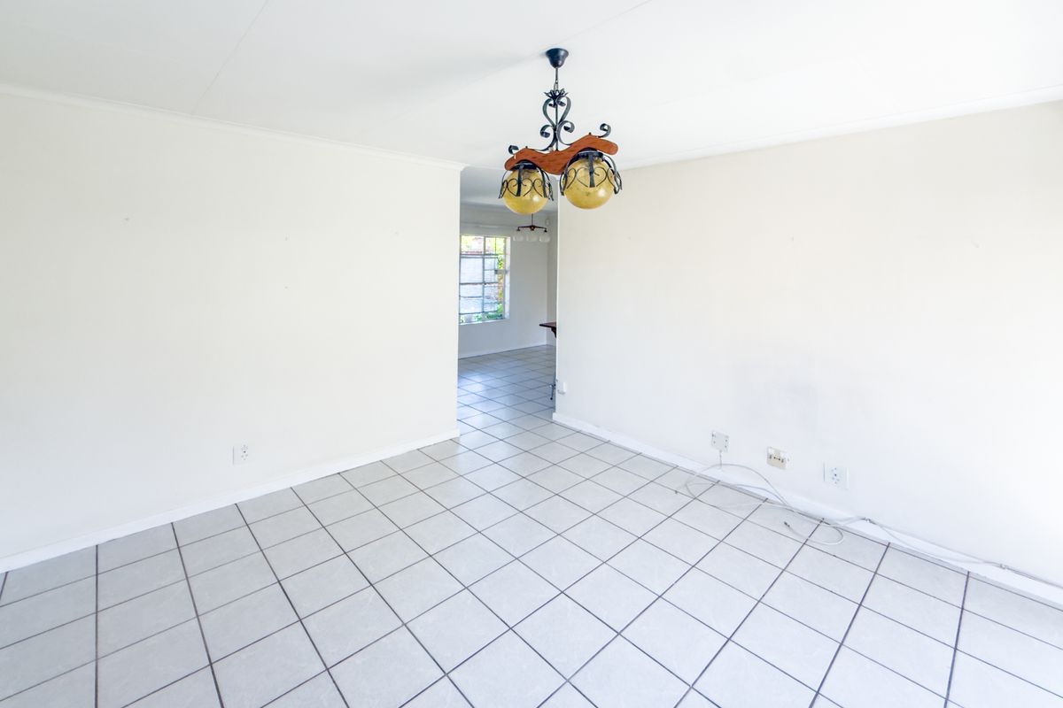 A bright, empty living area featuring neutral tiled flooring and a central ceiling light fixture, offering a blank canvas for interior design.