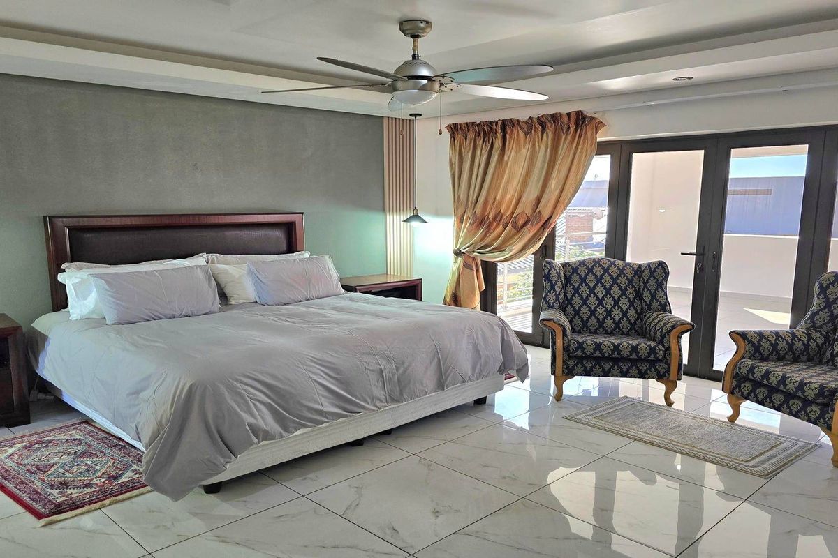 Spacious bedroom featuring polished tiled flooring, a modern ceiling fan, and large sliding glass doors providing access to an outdoor area.