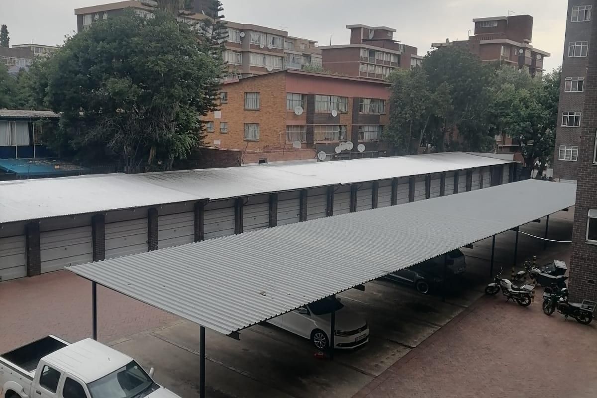 An elevated view of the apartment complex parking area featuring covered carports and paved driveway surfaces.