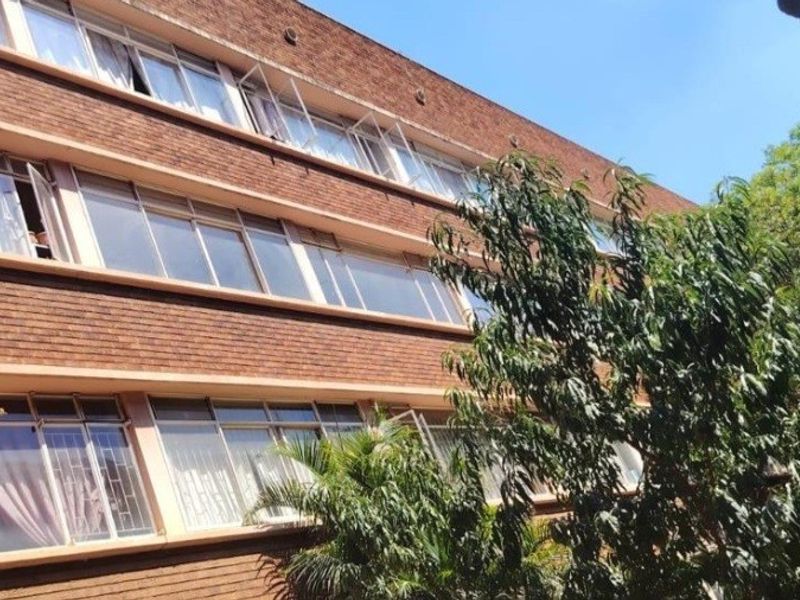A view of the multi-story apartment building facade featuring classic brickwork and large horizontal window banks.
