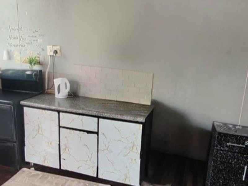 A compact kitchen area featuring basic cabinetry, laminate countertops, and a tiled backsplash, offering potential for modernization and improved layout efficiency.