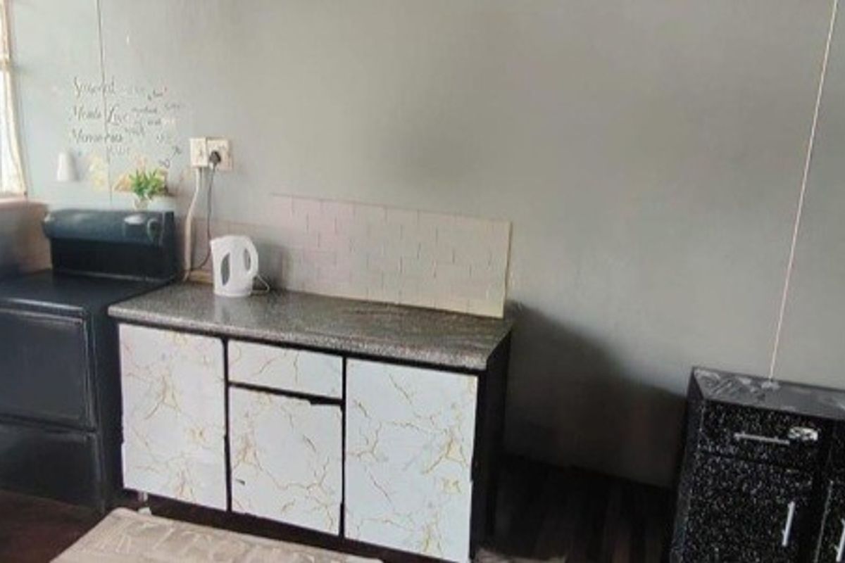 A compact kitchen area featuring basic cabinetry, laminate countertops, and a tiled backsplash, offering potential for modernization and improved layout efficiency.