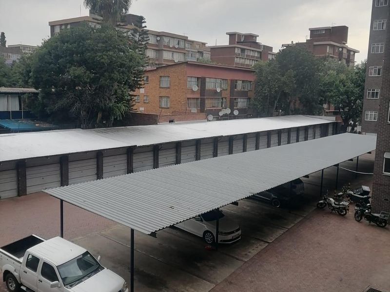 An elevated view of an apartment complex parking area featuring covered parking bays and paved driveway surfaces.