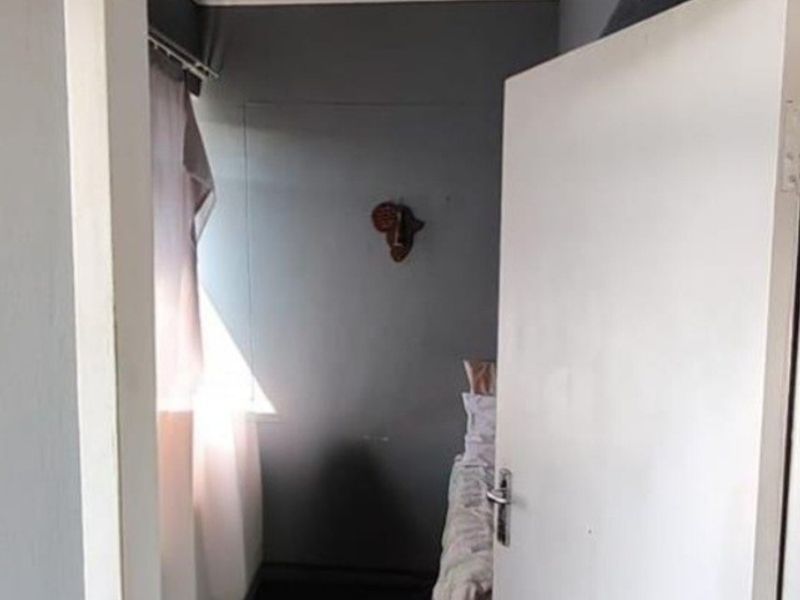A view into a bedroom featuring a transom window above the doorway and dark flooring.
