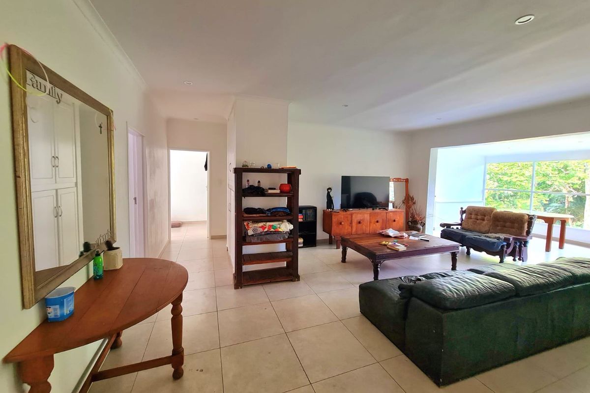Spacious living area featuring neutral tiled flooring, recessed lighting, and a large window providing natural light and garden views.