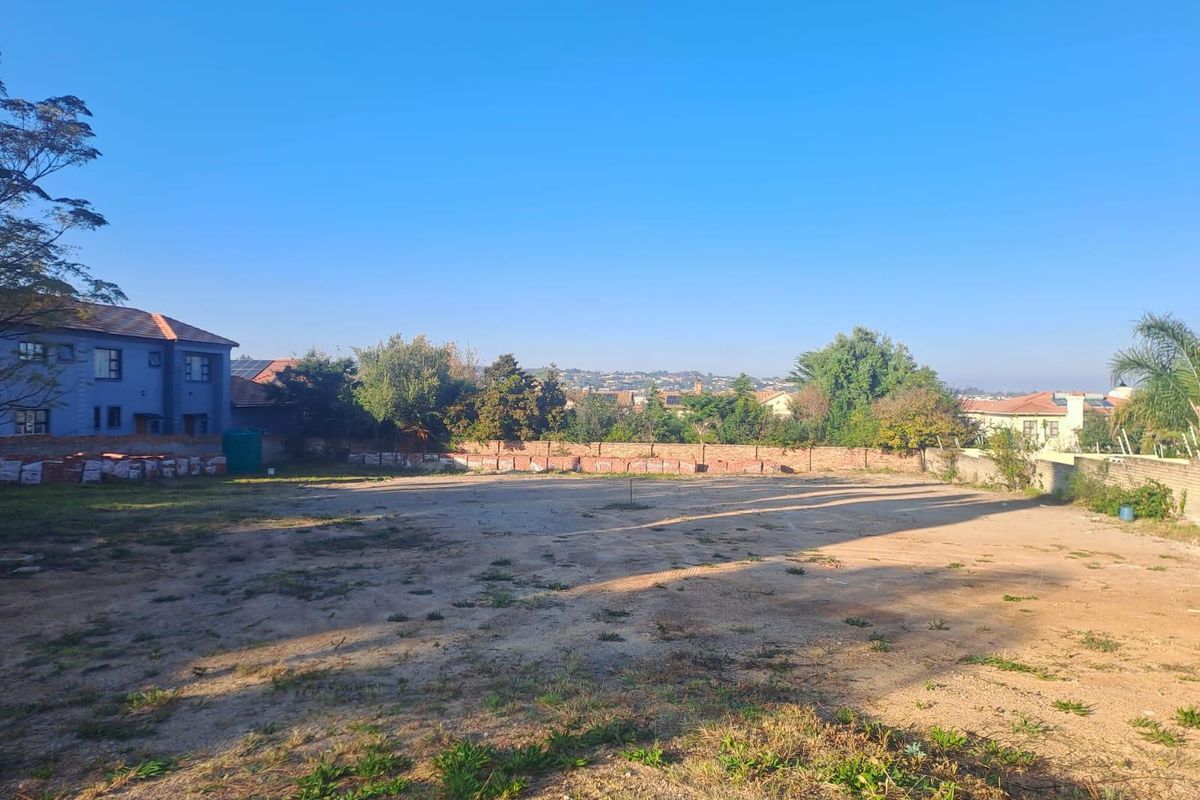 A vacant residential plot featuring a cleared surface and perimeter boundary wall, offering a blank canvas for future development.