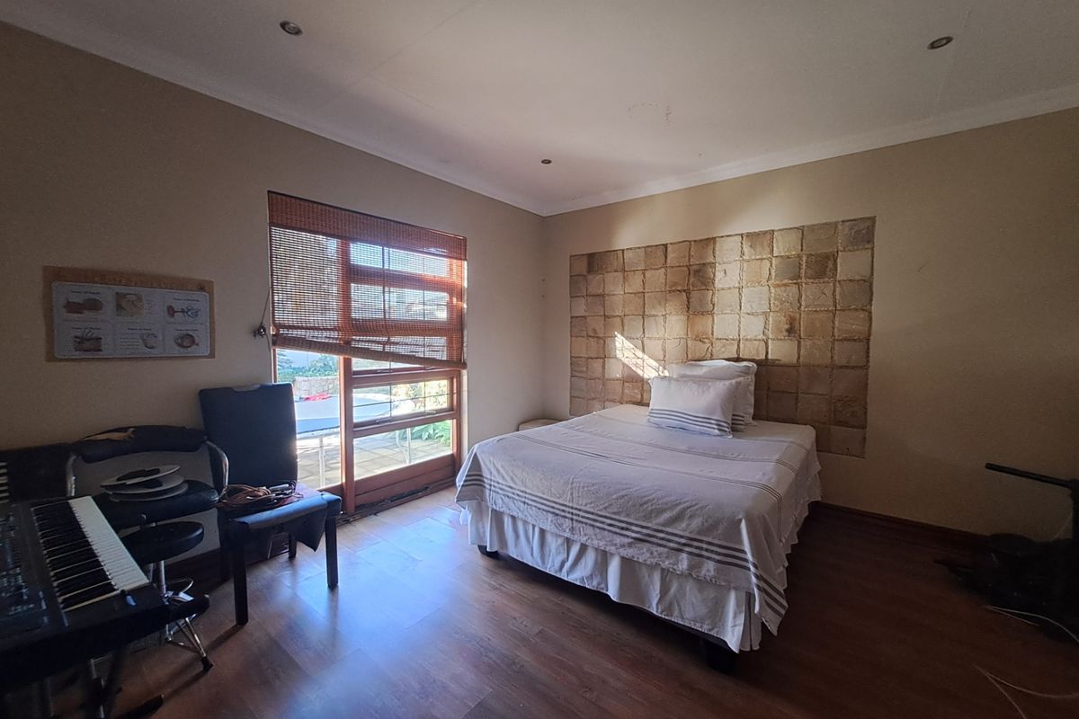 A bedroom featuring laminate flooring, a stone tile accent wall, and a sliding glass door providing natural light.