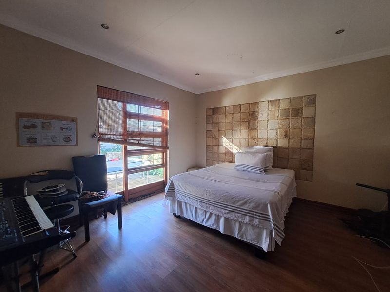 A bedroom featuring laminate flooring, a stone tile accent wall, and a sliding glass door providing natural light.