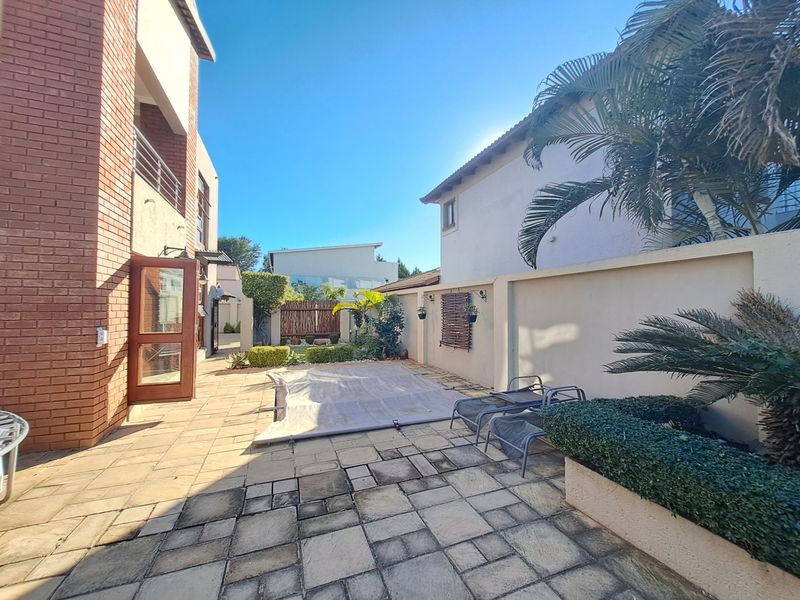 A private outdoor pool area featuring paved patio space, boundary walls, and direct access to the main residence.