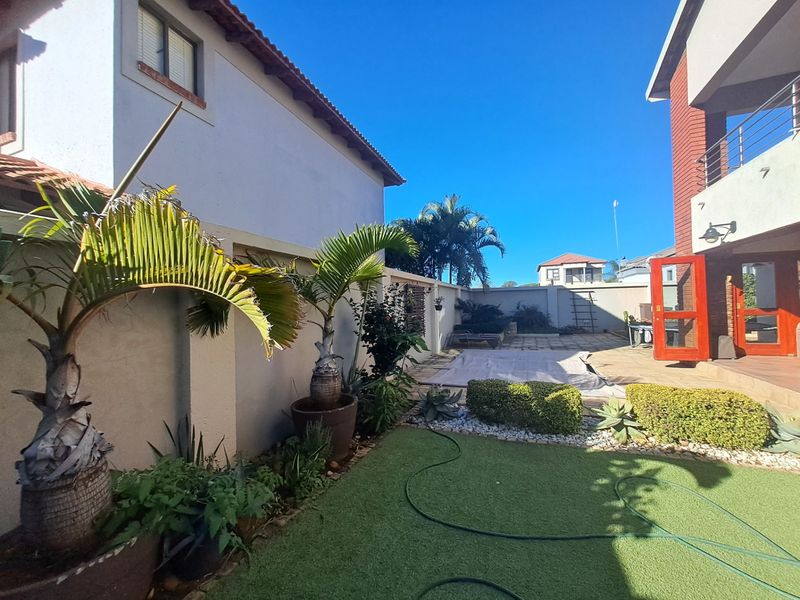 A private rear garden area featuring a paved patio, artificial lawn, and boundary walls, providing a low-maintenance outdoor space for relaxation.