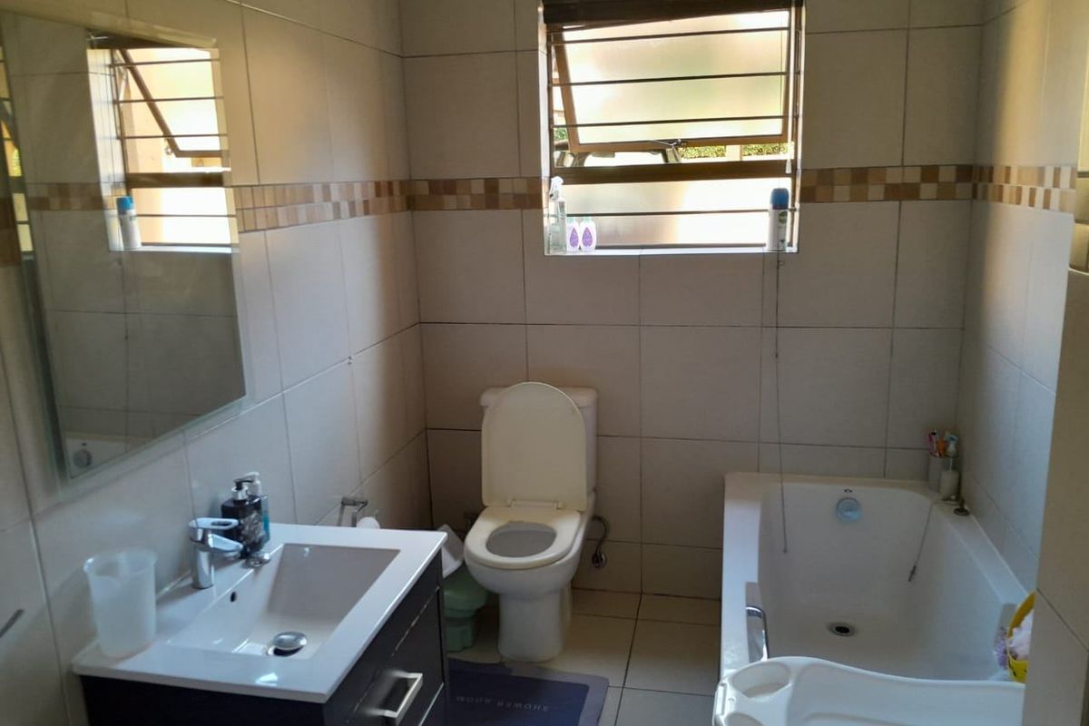 A functional bathroom featuring a vanity cabinet with basin, a standard toilet, and a bathtub with full-height wall tiling.