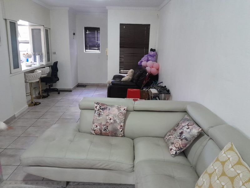 Open plan living area featuring tiled flooring, a breakfast bar with integrated counter, and venetian blinds on the windows.