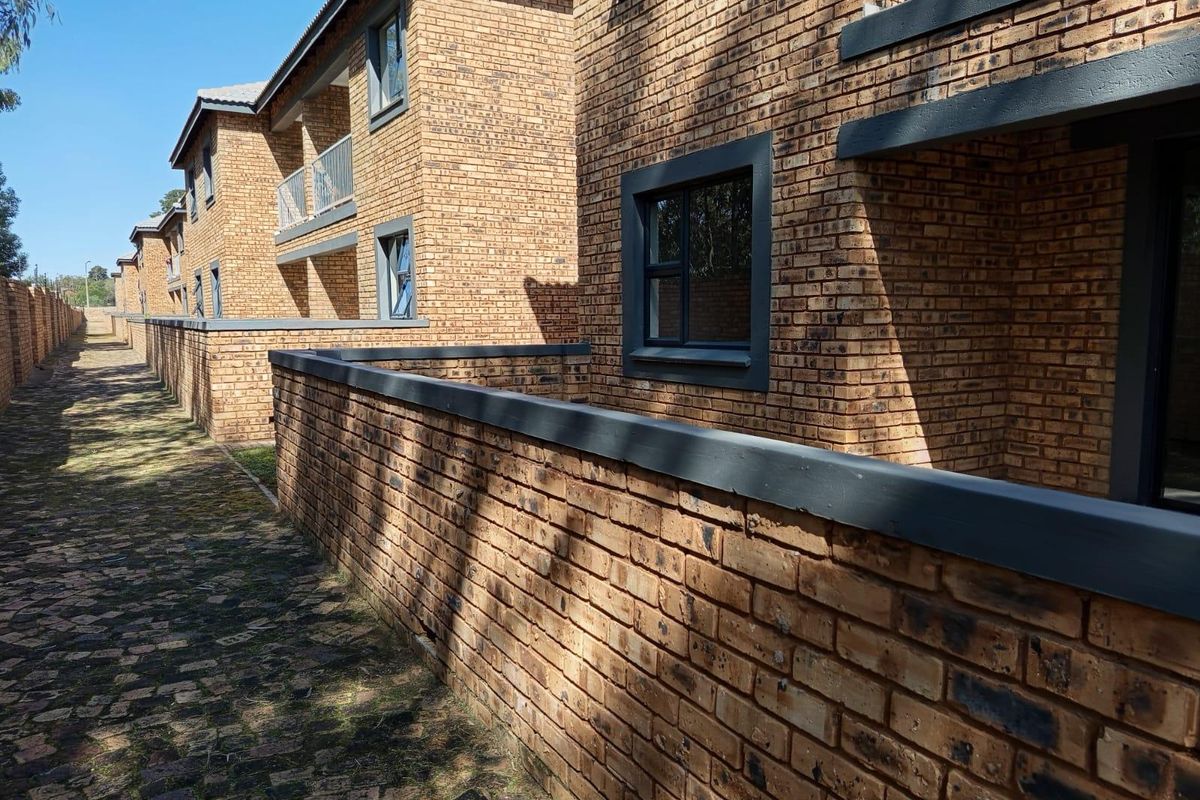 Exterior view of a multi-story apartment complex featuring face brick construction, paved walkways, and private balconies.