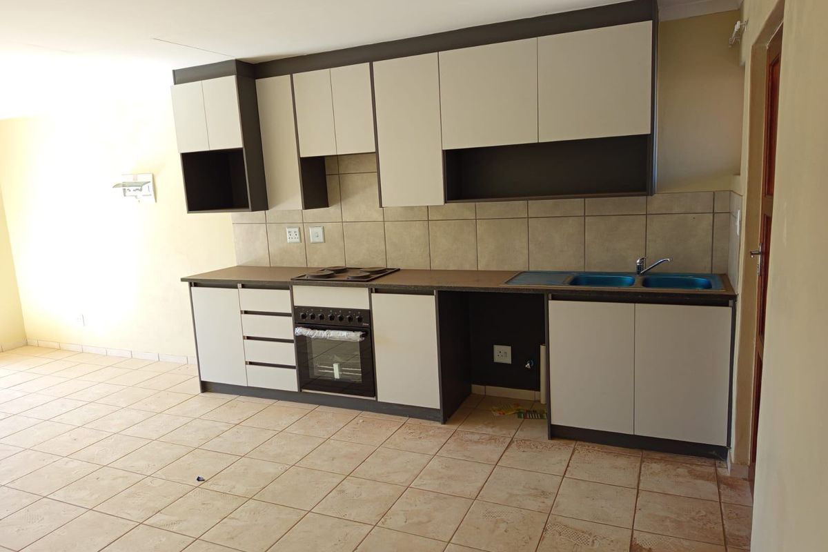 A functional kitchen featuring built-in cabinetry, a double sink, and integrated oven and hob, set within an open-plan living space.