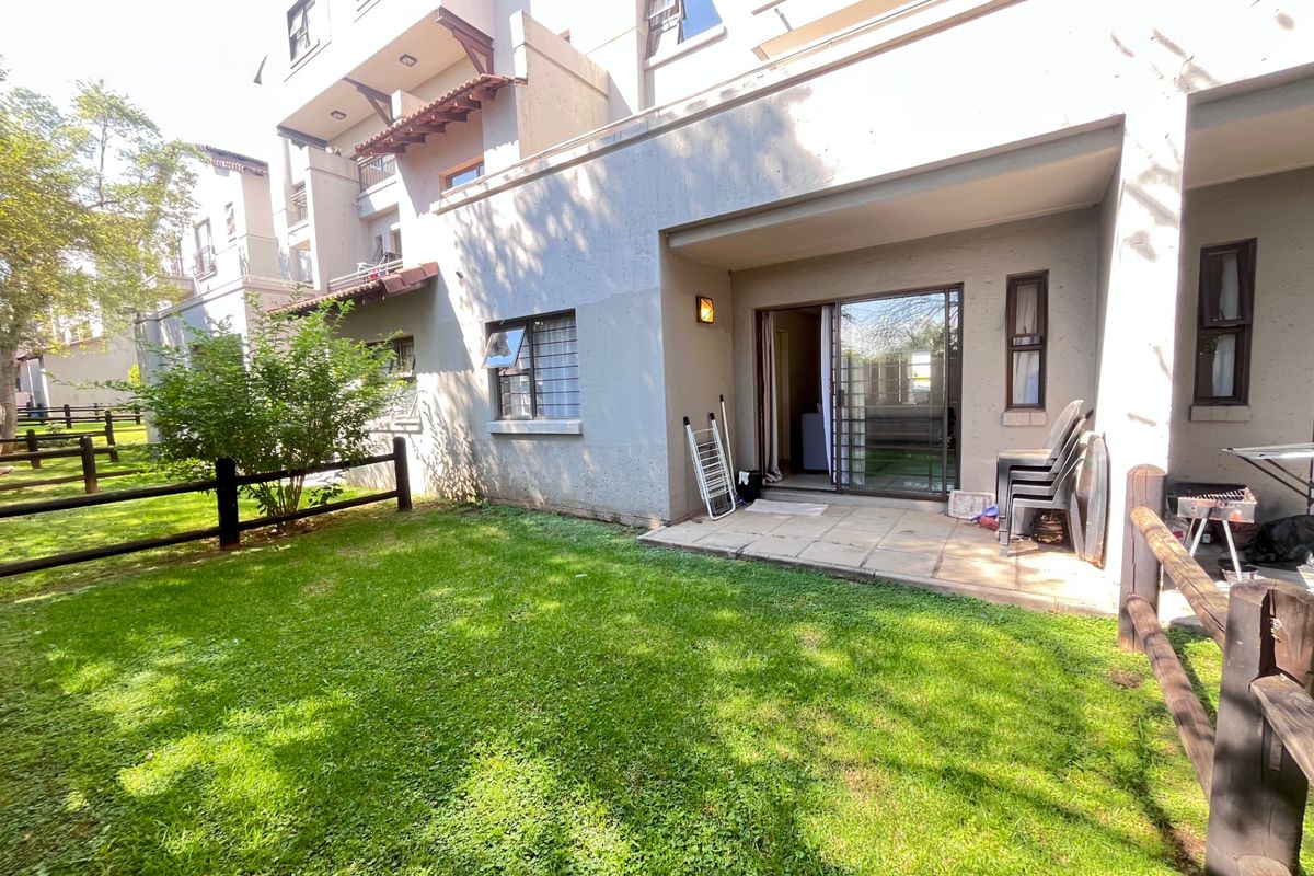 Ground floor apartment featuring a private paved patio area leading onto a shared garden space with timber fencing.