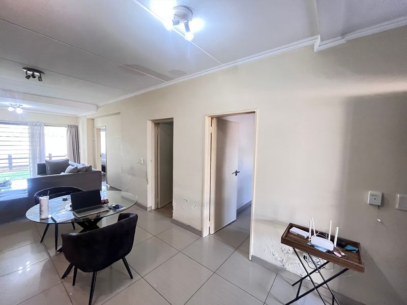 Open plan living area featuring tiled flooring and multiple access points to adjacent rooms, showing signs of wear on walls and ceiling.