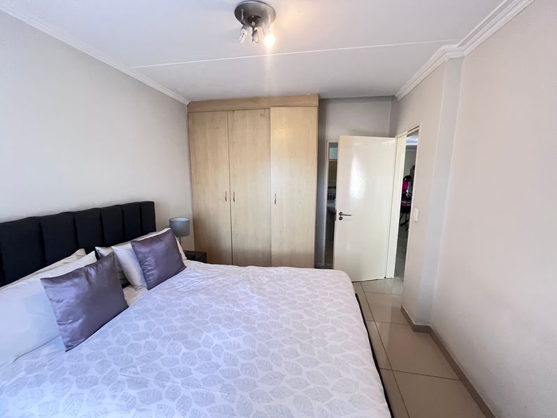 A bedroom featuring tiled flooring, a built-in wardrobe, and ceiling cornice detailing.