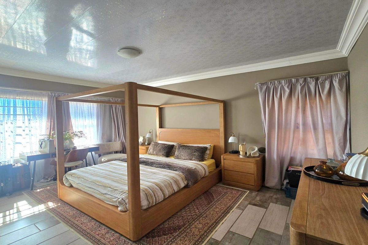 Spacious bedroom featuring tiled flooring, crown molding, and ample natural light from multiple windows.