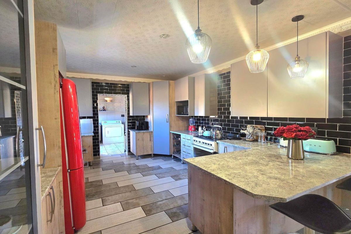Modern kitchen featuring stone-look countertops, black subway tile backsplash, pendant lighting, and a functional layout with an adjoining laundry area.
