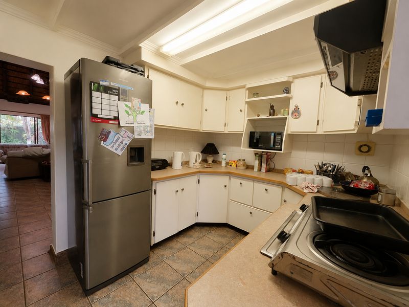 A functional kitchen featuring built-in cabinetry, laminate countertops, and tiled flooring, offering a practical layout with direct access to the adjacent living area.