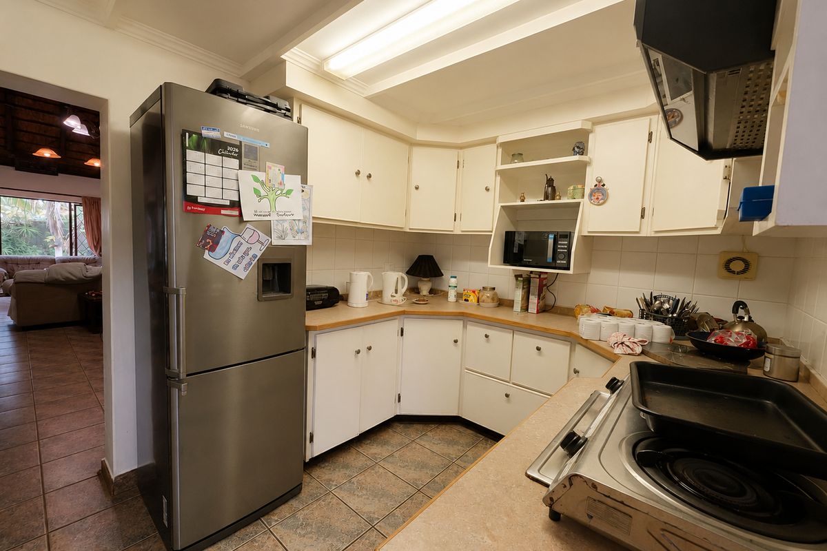 A functional kitchen featuring built-in cabinetry, laminate countertops, and tiled flooring, offering a practical layout with direct access to the adjacent living area.