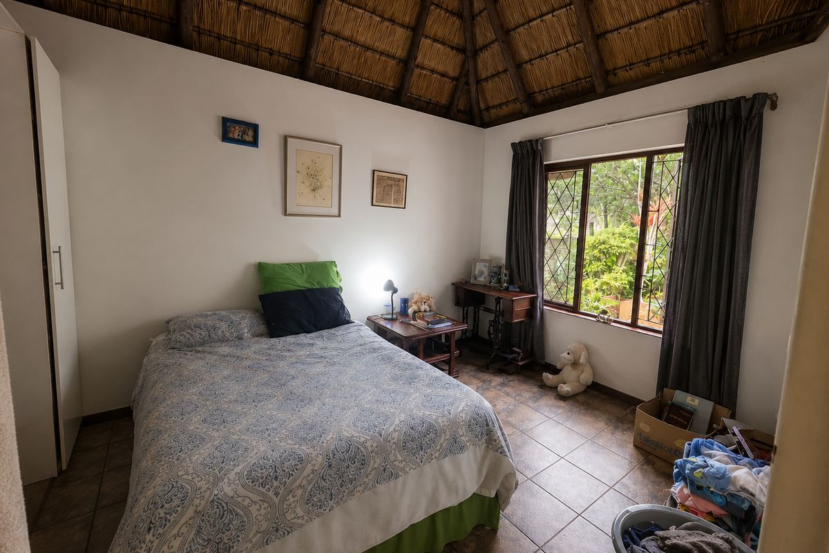A bedroom featuring a traditional thatched roof ceiling, tiled flooring, and a built-in wardrobe, offering a cozy and rustic atmosphere.