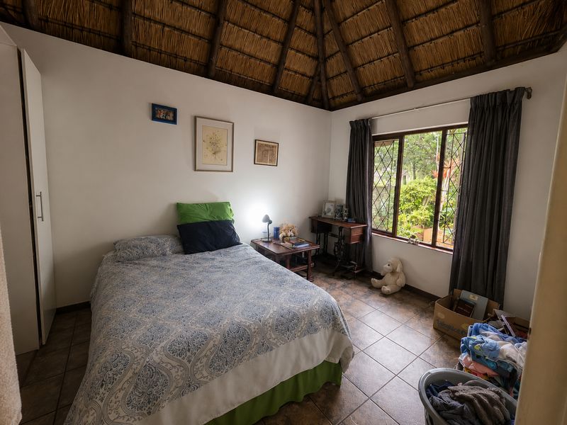 A bedroom featuring a traditional thatched roof ceiling, tiled flooring, and a built-in wardrobe, offering a cozy and rustic atmosphere.